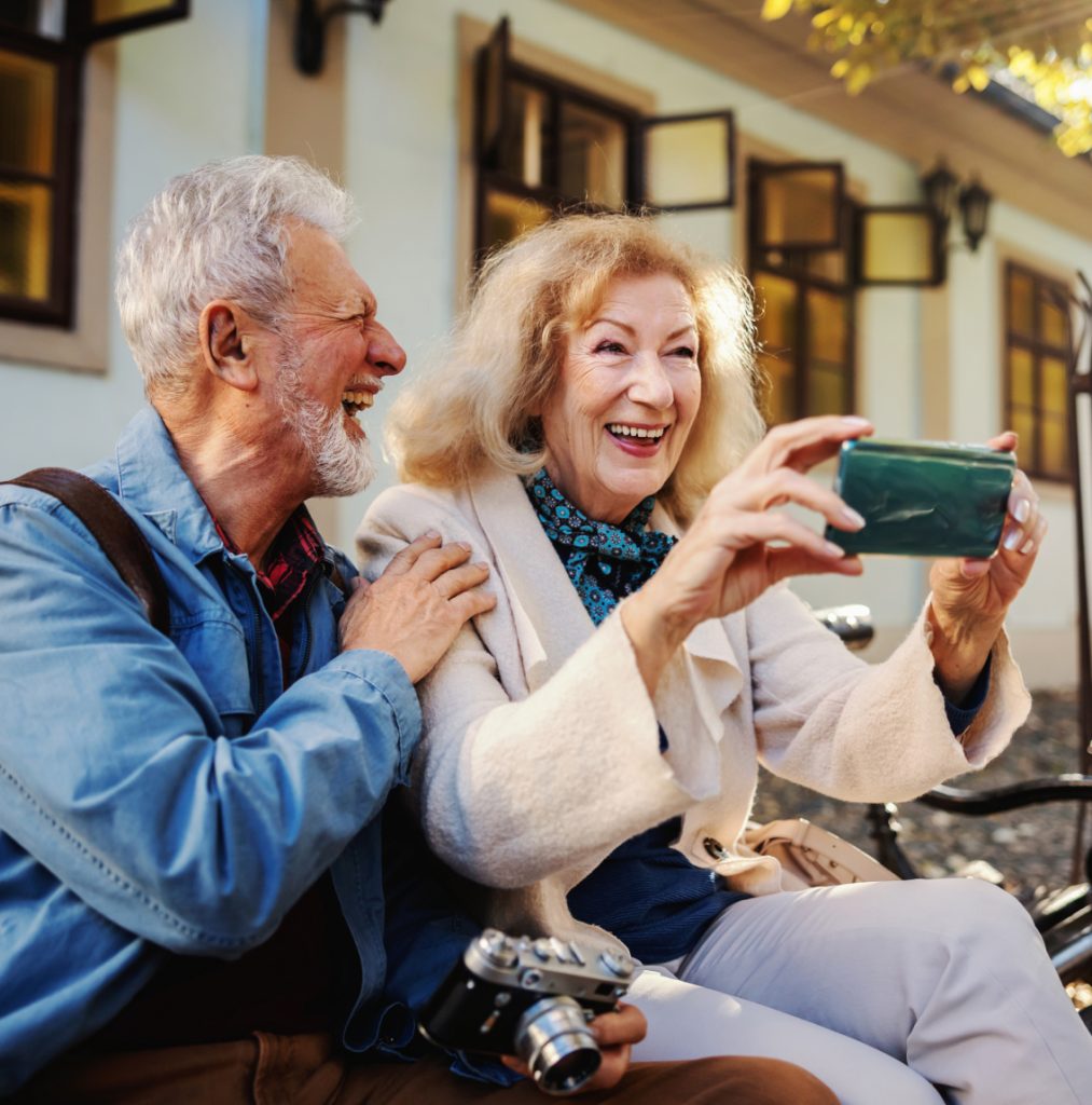 A laughing elderly couple sitting outside relaxing