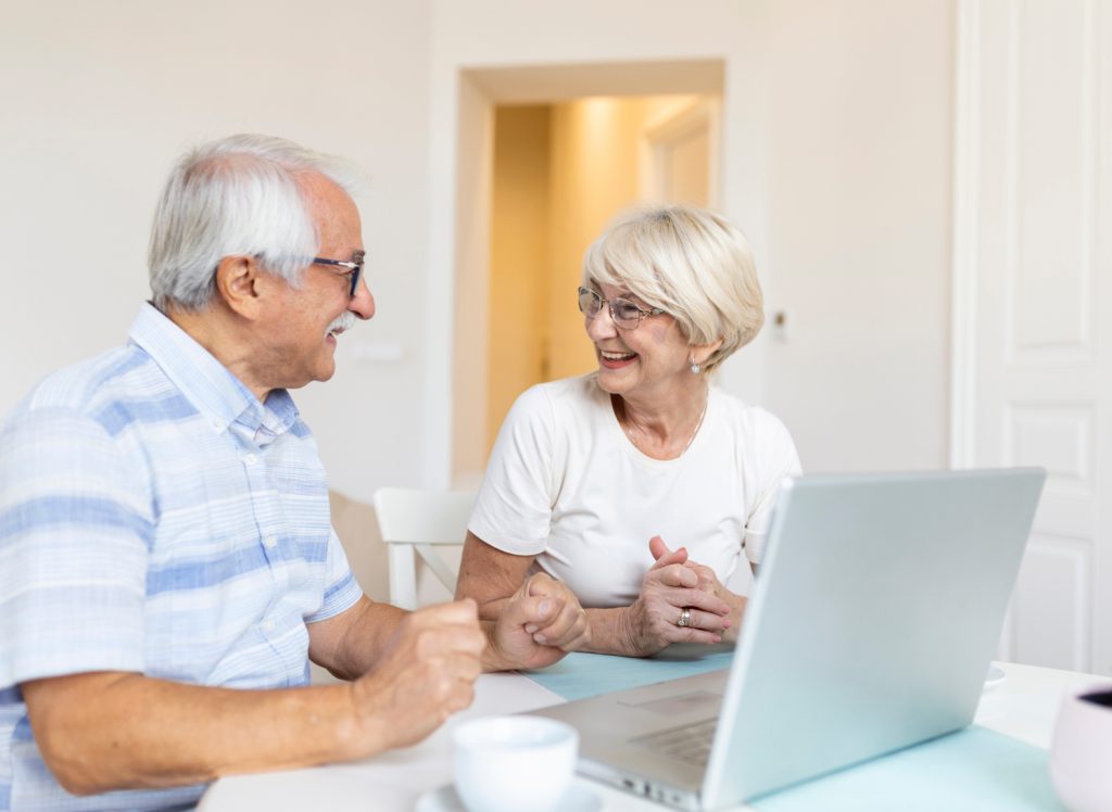 An elderly couple looking at OTC Hearing Aid options on a laptop