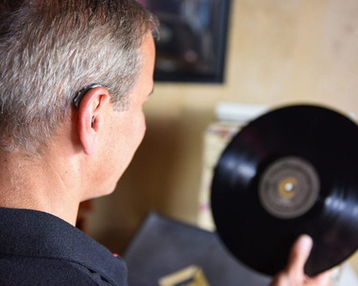A man listening to a record while wearing an OTC hearing aid